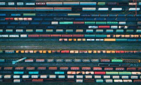 Freight trains and containers on tracks from above illustrate the complexity of port logistics optimization